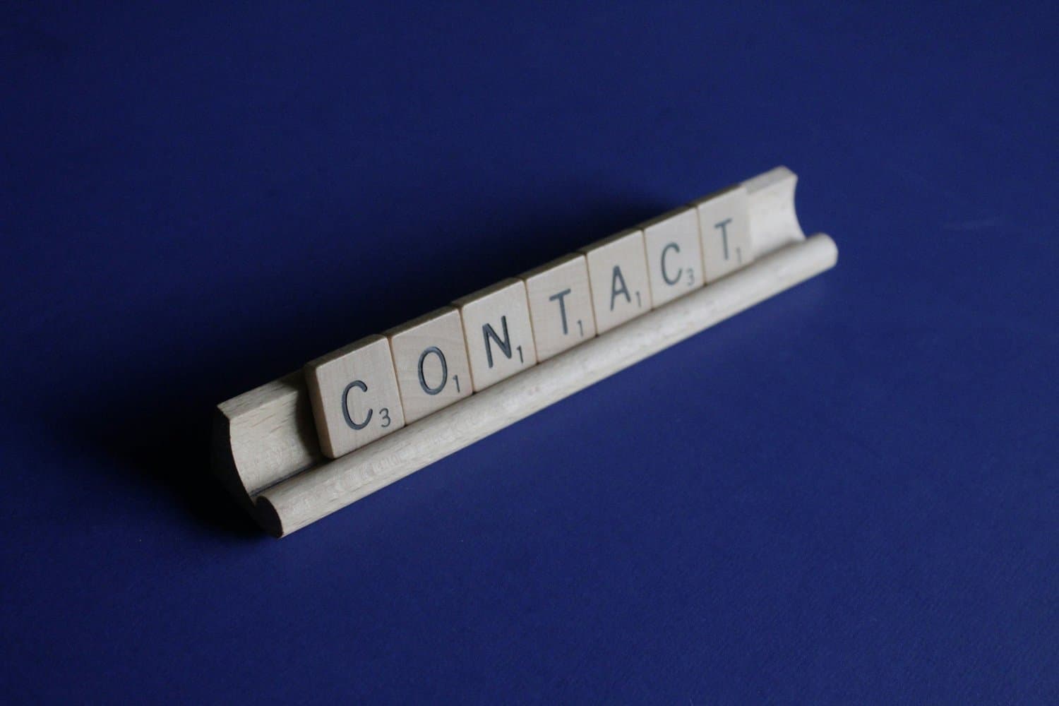 Wooden letter tiles spelling out 'CONTRACT' on a blue background.
